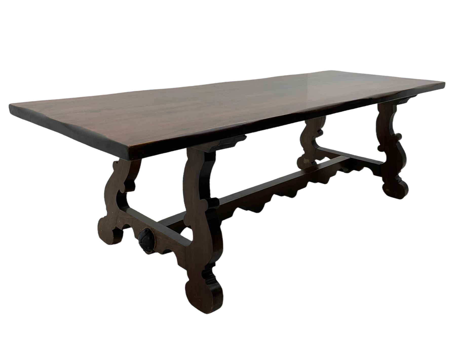 Large Spanish hardwood dining table, on shaped open ends supports joined by stretcher 
