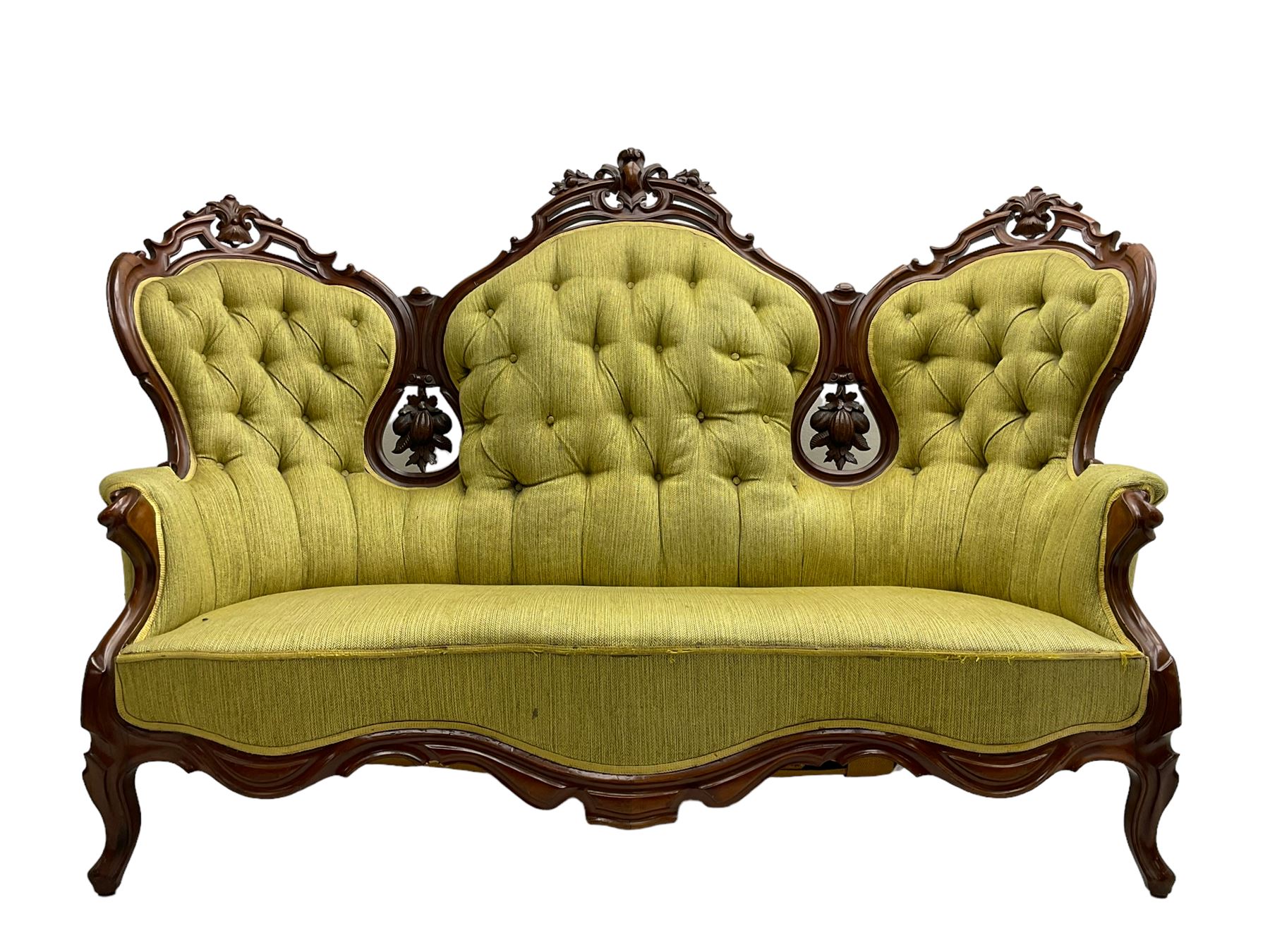 Victorian walnut settee, triple back with pierced and scroll-carved cresting rails over carved fruit and foliage decoration, upholstered in buttoned green fabric, serpentine seat and carved apron, on cabriole feet