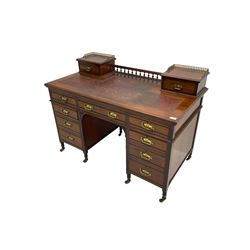 Maple & Co - Edwardian mahogany twin pedestal desk, the raised back with spindle gallery and open shelf to centre flanked by two trinket drawers, rectangular top with inset writing surface, fitted with one long and eight short graduating drawers flanked by fluted uprights, raised on brass and ceramic castors, stamped to central drawer
