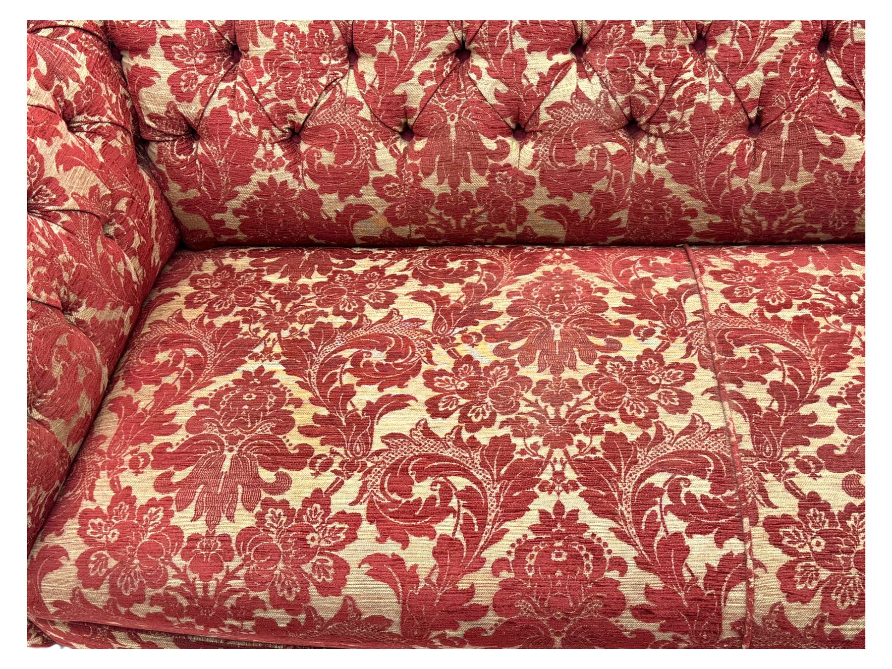 Late 20th century upholstered Chesterfield sofa, in red damask floral fabric, with deep buttoned back and arms, scrolled arms at equal height to back, on turned front supports