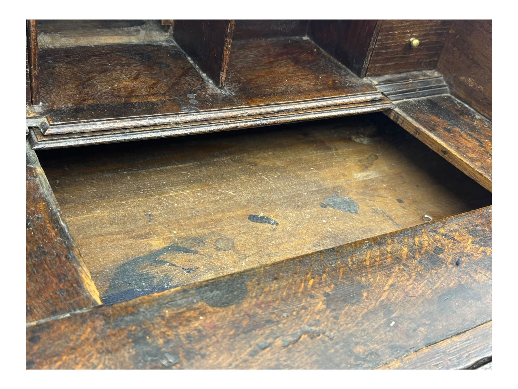 George III oak bureau, sloped fall-front enclosing a fitted interior with pigeonholes, small drawers, and a central compartment, over two short and two long drawers, brass escutcheons and drop handles, raised on bun feet