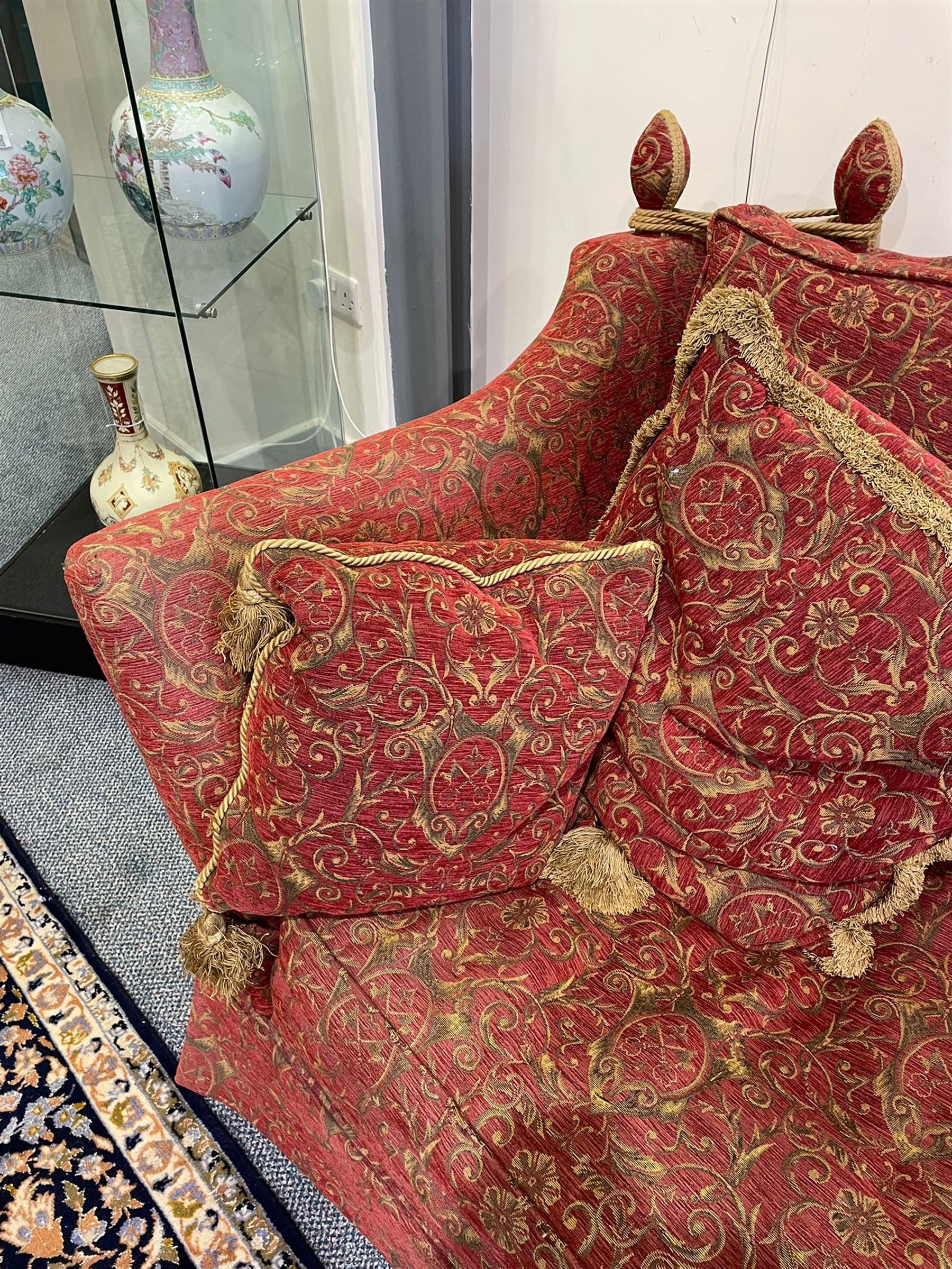 Large Knole design hardwood-framed three-seat drop-arm sofa, upholstered in crimson fabric decorated with trailing acanthus leaves and shields, together with scatter cushions 