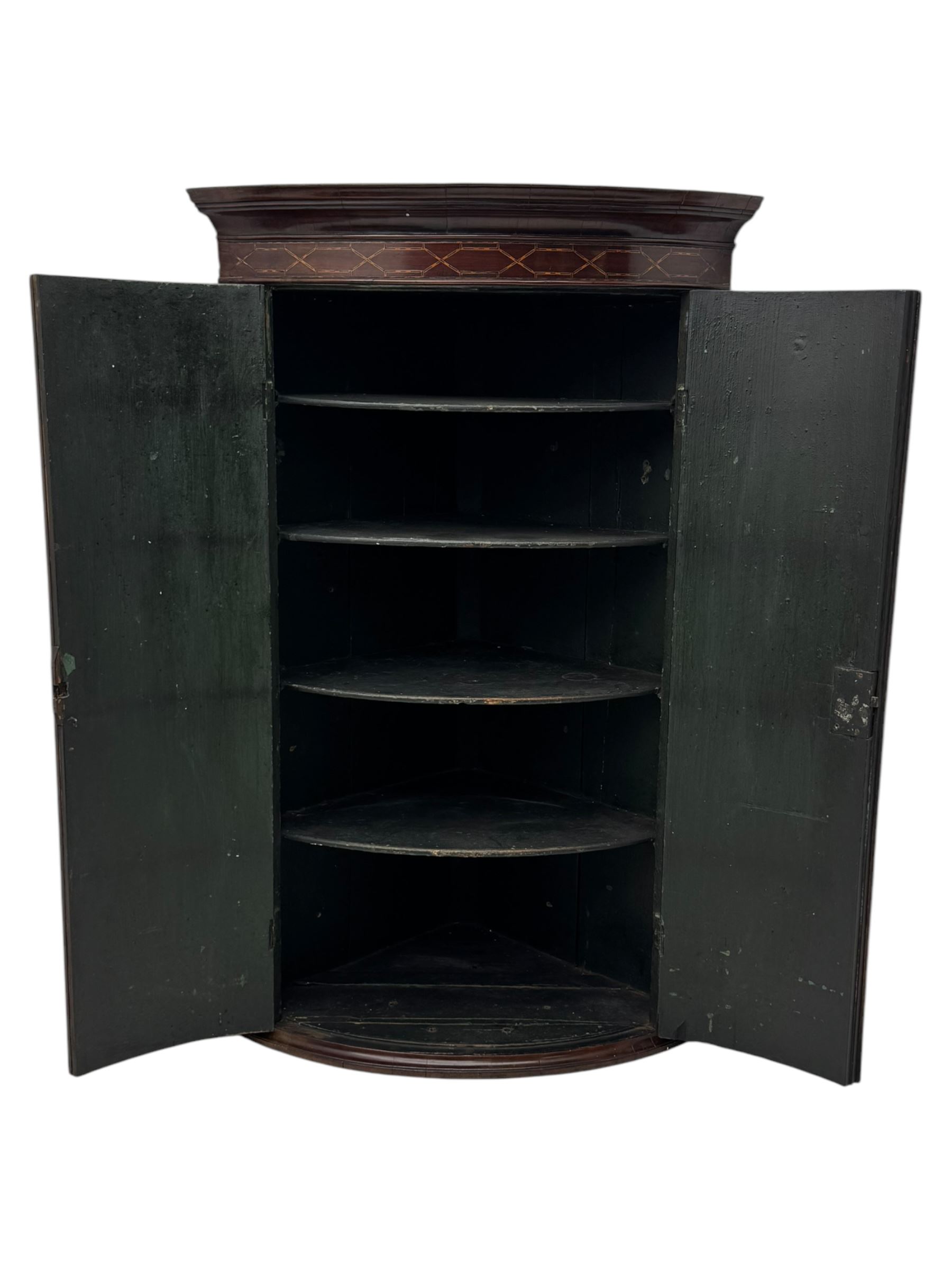 Late Georgian mahogany hanging corner cupboard, moulded cornice with interlaced boxwood stringing pattern above two cupboard doors inlaid with wave form boxwood stringing and four internal shelves 