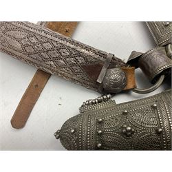 Omani Khanjar dagger, the 19cm curved blade with pronounced medial rib to either side, waisted hilt with dome shaped pommel and silver covered horn grip decorated with filigree bands, floral motifs and beadwork; in an intricately filigree decorated silver and leather scabbard with silver rings woven into the belt mount and fitted with original silver thread-work belt L34cm overall belt length 94cm