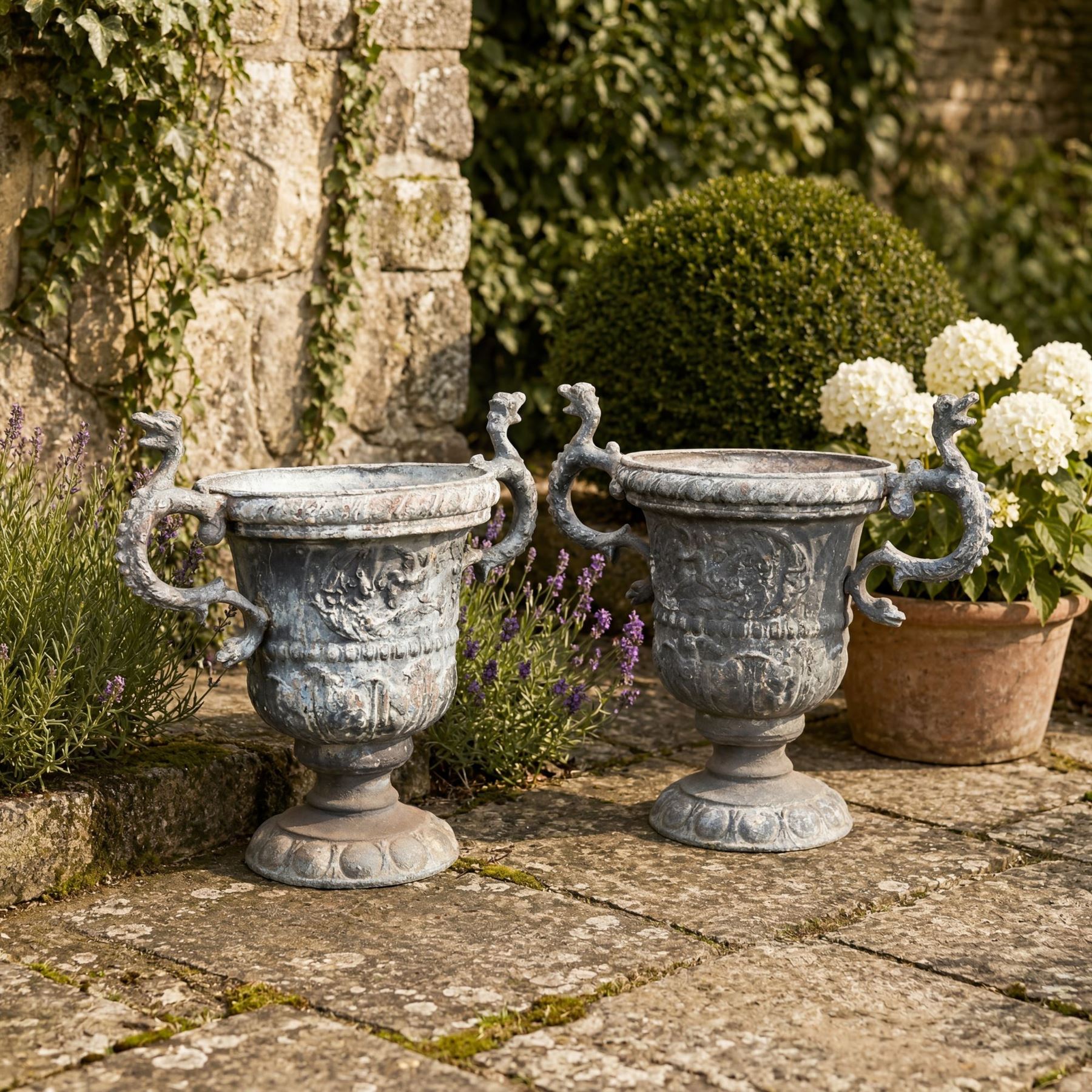 Impressive pair of early highly decorative lead garden urns, griffin handles with ornate decoration depicting cherubs and laurel wreath
