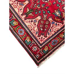 Persian Azerbaijan crimson ground rug, the field decorated with central floral motif and surrounded by trailing floral branches, enclosed within a shaped outer band with further floral decoration, the border with repeating flower heads, geometric guard stripes 