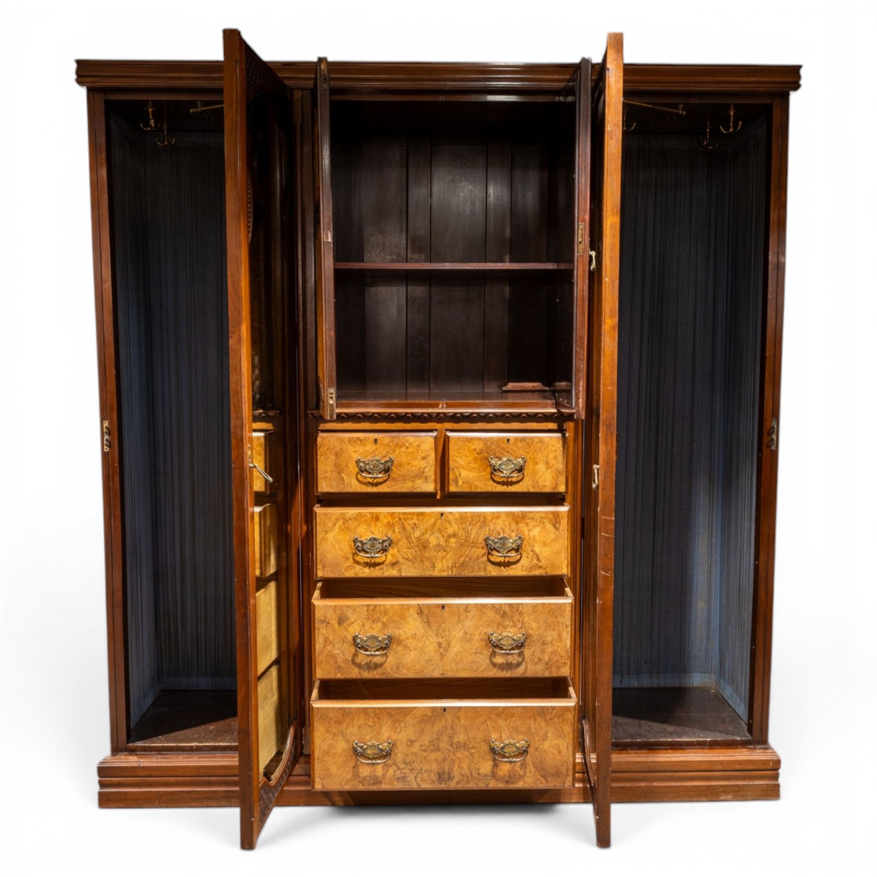 Edwardian figured walnut triple combination wardrobe, moulded cornice above a three part wardrobe, central section with figured walnut panelled doors, above two over three drawers, flanked by mirrored doors enclosing hanging hooks, raised on a plinth