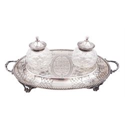 Victorian silver desk stand, of oval form, with beaded rim and twin handles, engraved with lattice and floral decoration and with personal engraving to centre 'Presented to the Revd James Connor by members of his congregation and other friends in remembrance of his faithful ministerial services amongst them, Thytherton Sept 1868' with two recesses, each containing a faceted glass inkwell with star cut base and silver covers, hallmarked H J Lias & Son, London 1867, including inkwells H13cm