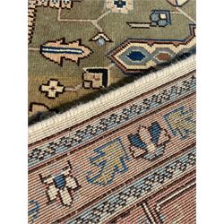 Persian Heriz pale olive and ivory ground carpet, large quatrefoil medallion with palmettes, the surrounding field decorated with trailing leafy branches and stylised plant motifs, peach ground borders with overall floral pattern, within guard stripes 