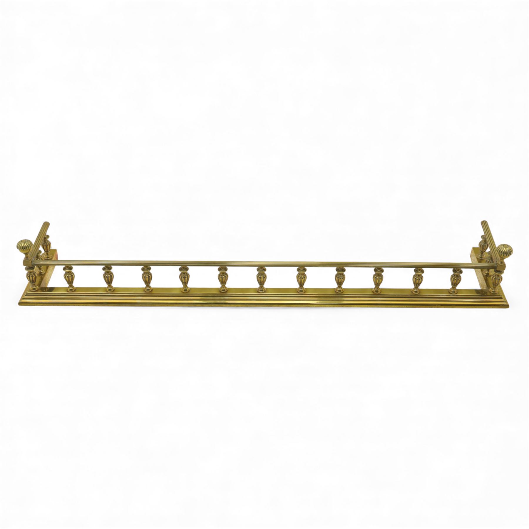 Edwardian brass fire kerb, with reeded and stepped base supporting baluster uprights and reeded top 