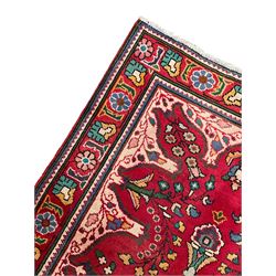 Persian Azerbaijan crimson ground rug, the field decorated with central floral motif and surrounded by trailing floral branches, enclosed within a shaped outer band with further floral decoration, the border with repeating flower heads, geometric guard stripes 