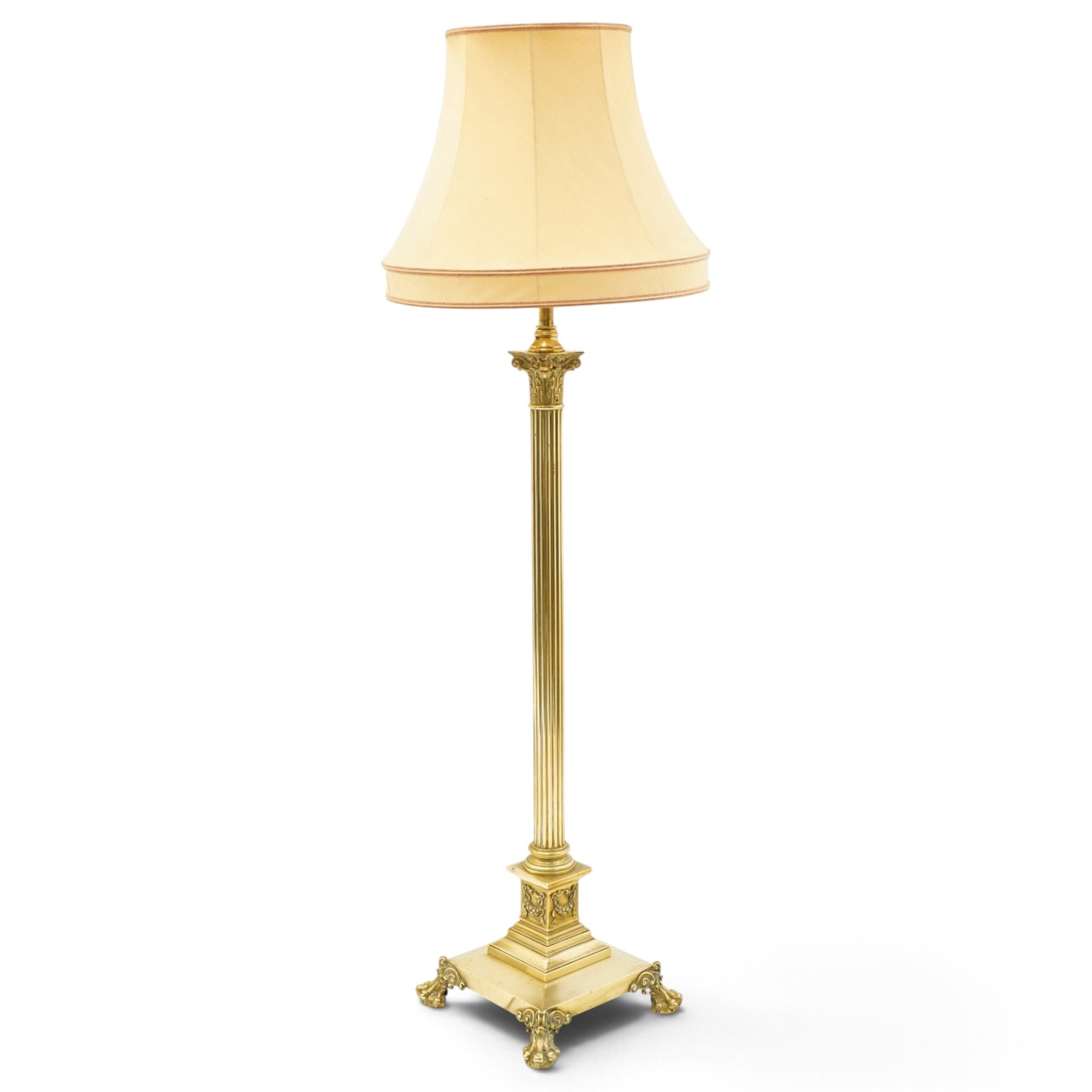 Late Victorian Neoclassical brass standard lamp with shade, the composite Ionic and Corinthian acanthus capital over a reeded column, terminating to a stepped platform base with applied festoon ornament, raised on four scrolling ball-and-claw feet