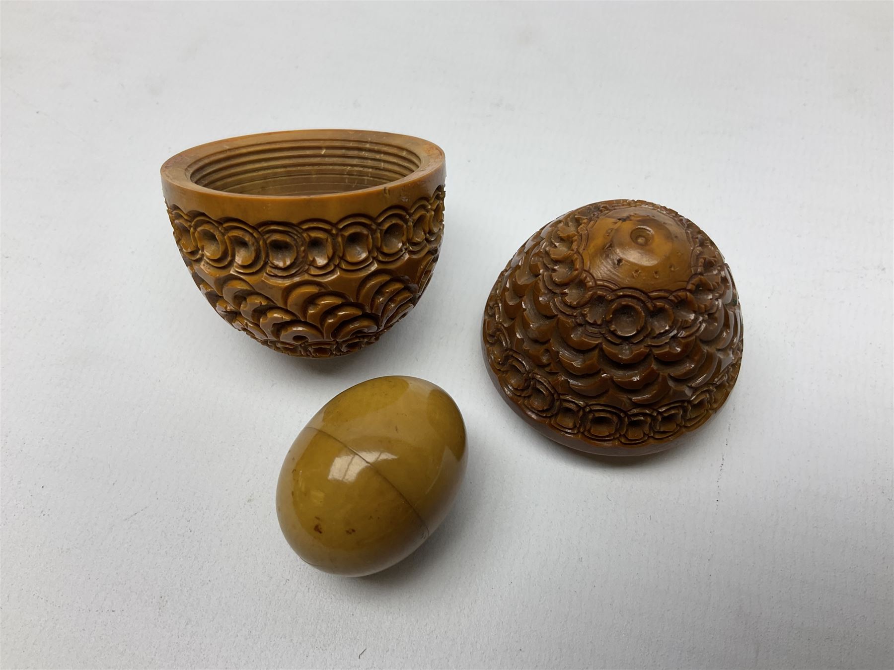 Three 19th century coquilla nut pomanders or flea catchers, each of egg shaped form with carved and pierced decoration and screw threaded join, largest example 6cm