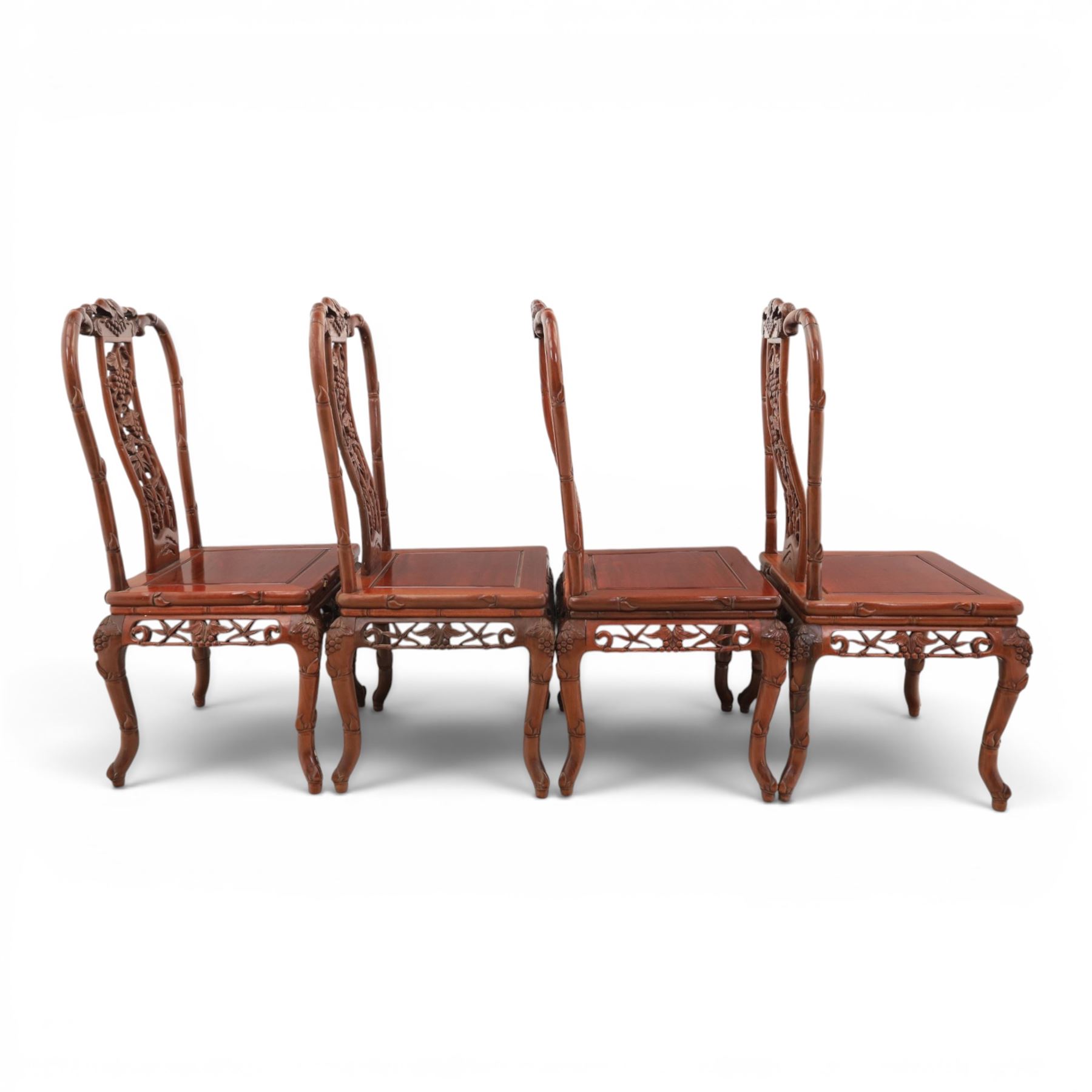 20th century Chinese ornately hardwood dining table and chairs, circular table with 'Lazy Susan' top with pierced carved frieze, raised on a quadriform base with carved foliate detail, the chairs en suite with carved pierced detailing  