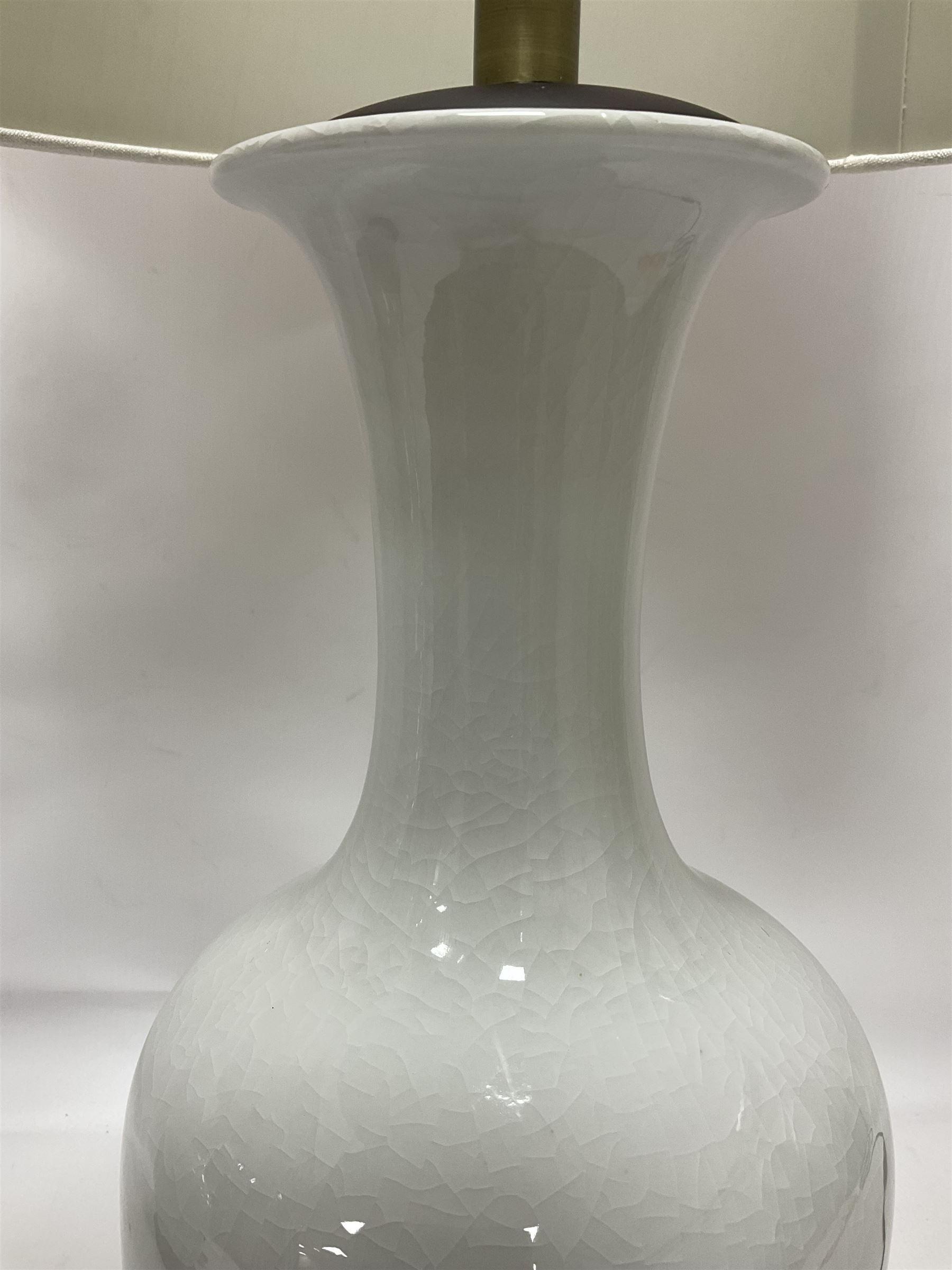 Pair of Chinese ivory crackle glazed table lamps, each of bottle form, raised upon circular hardwood base, excluding fittings H43cm