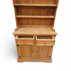 20th century stripped pine dresser, the open rack with dentil frieze and fixed shelves over a cupboard base with two drawers and fielded panel doors, flanked by stop-fluted uprights, on a moulded plinth