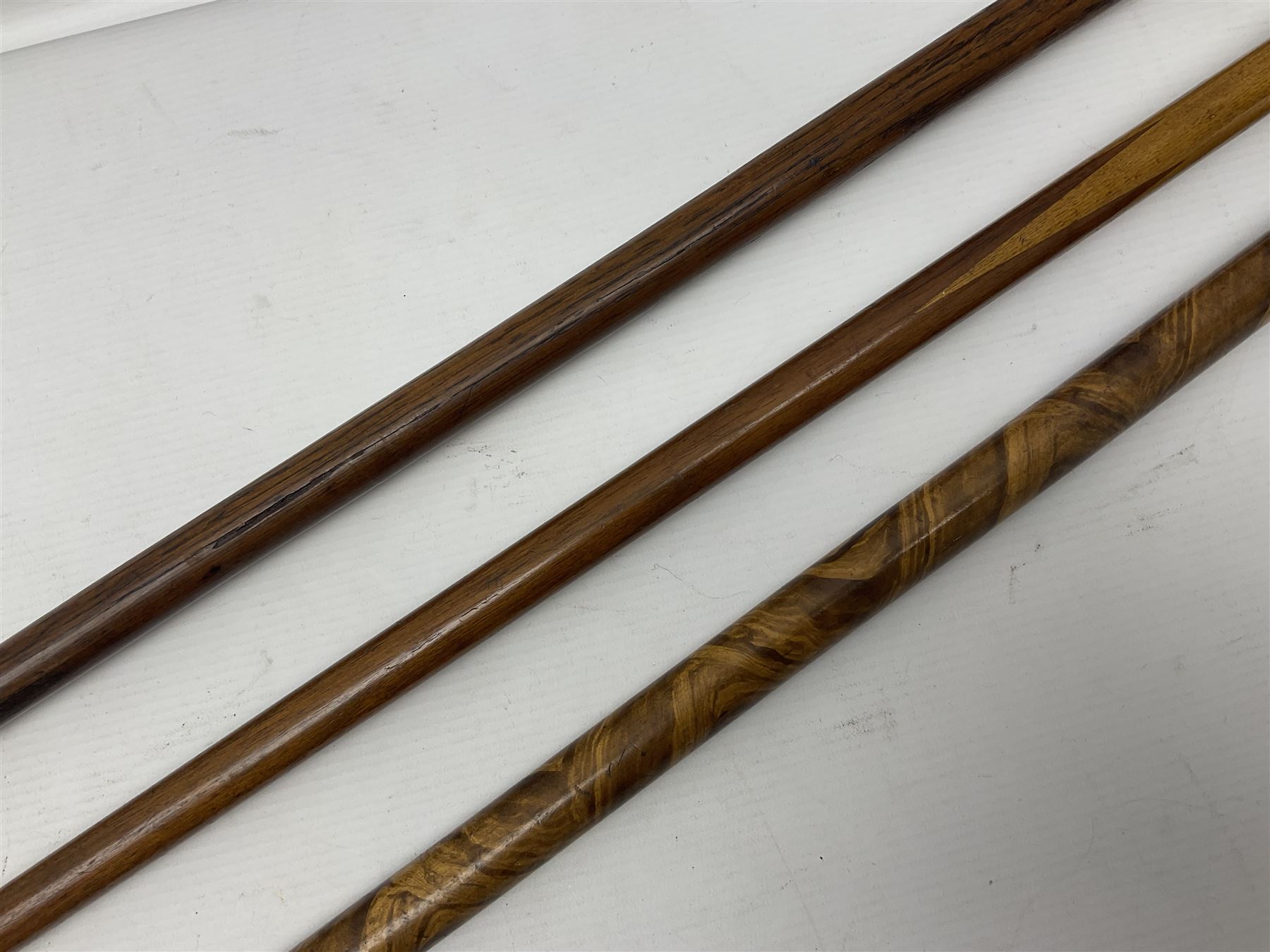 Three early 20th century walking sticks, to include a smoking pipe walking stick, the cane opening to reveal a concealed pipe, and a wooden walking cane, the metal cover with inscription 'bell metal and wood of York Minster, Burnt May 20 1840, and a turned wooden walking stick, with marquetry checkerboard pommel, tallest L90cm