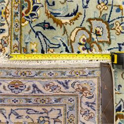 Central Persian Kashan hand-knotted carpet, pale celadon blue ground, decorated with an all-over central floral and foliate design with rosette medallion incorporating scrolling vine work, palmettes, and stylized blossoms  highlighted in tones of indigo, ivory, gold, and powder blue, enclosed by a cream ground border, flanked by multiple guard stripes, with cotton fringe ends 