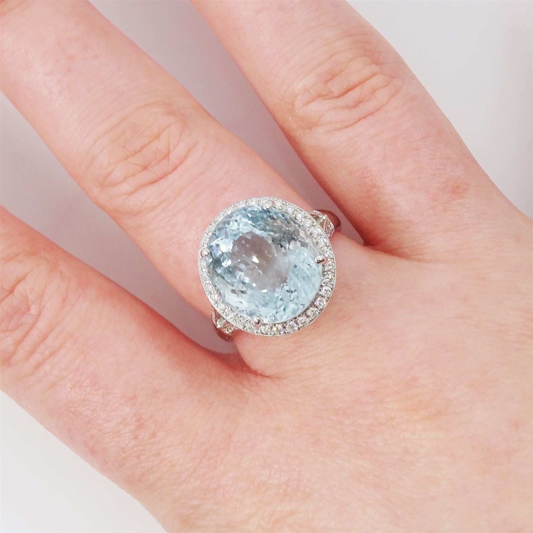 18ct white gold aquamarine and diamond cluster ring, single oval cut aquamarine of approx 8.20 carat, surrounded by milgrain set round brilliant cut diamonds, with diamond gallery and split diamond set shoulders, stamped 750, total diamond weight approx 0.30 carat
