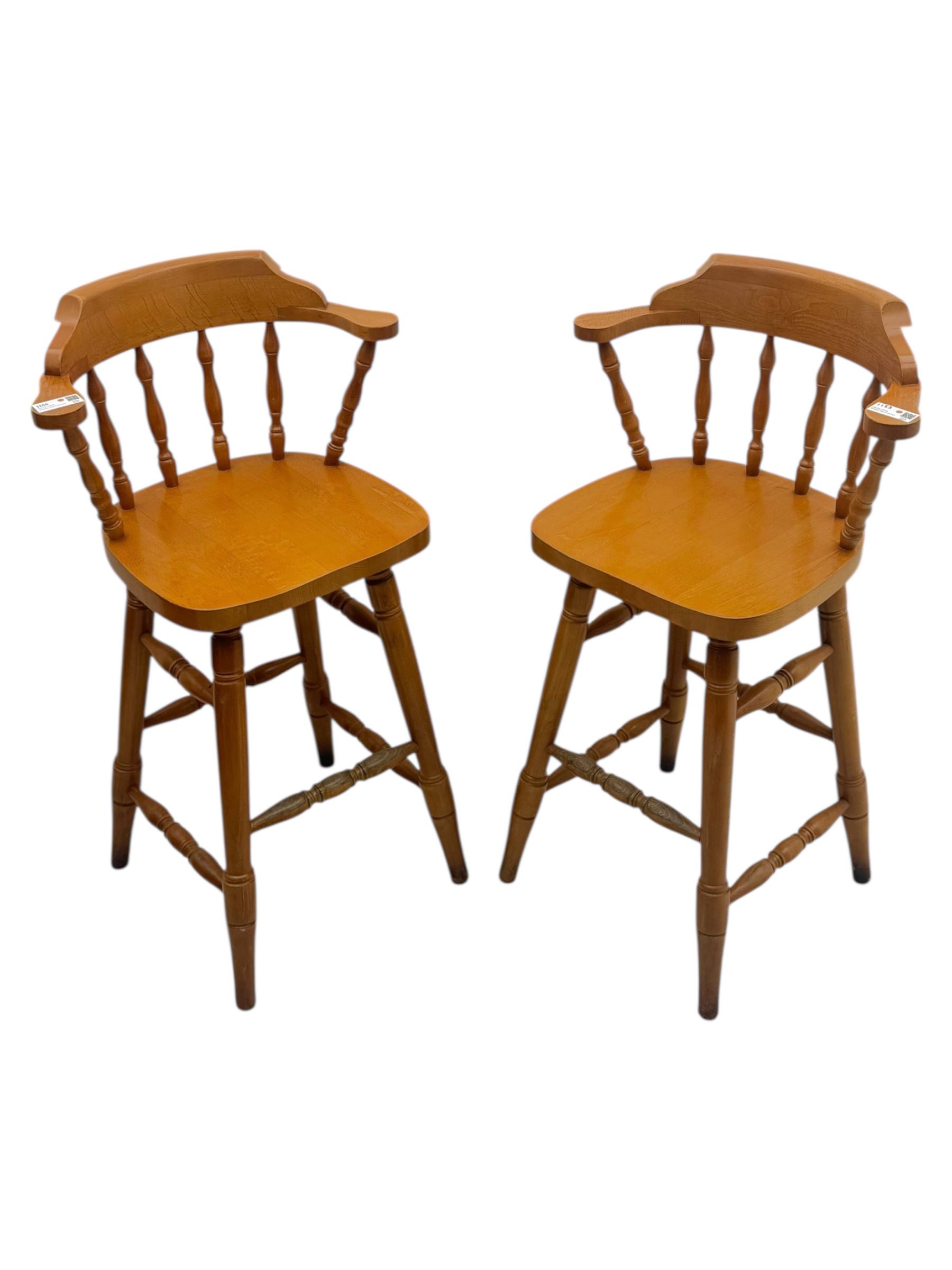 Pair of late 20th century beech bar stools, with curved top rail and turned spindle back, shaped seat over four turned legs united by multiple stretchers