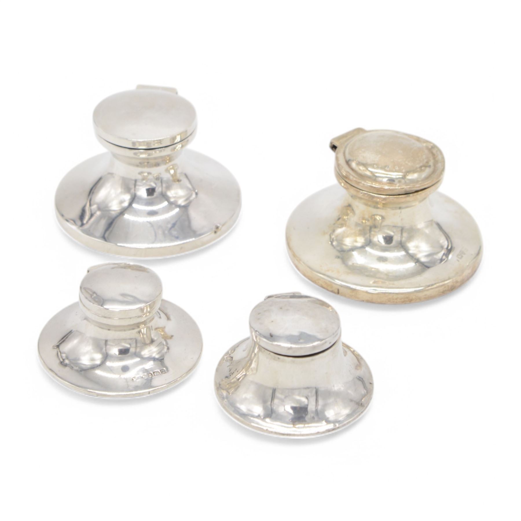 Four early 20th century silver mounted capstan inkwells, all of typical circular form with hinged covers, all hallmarked 