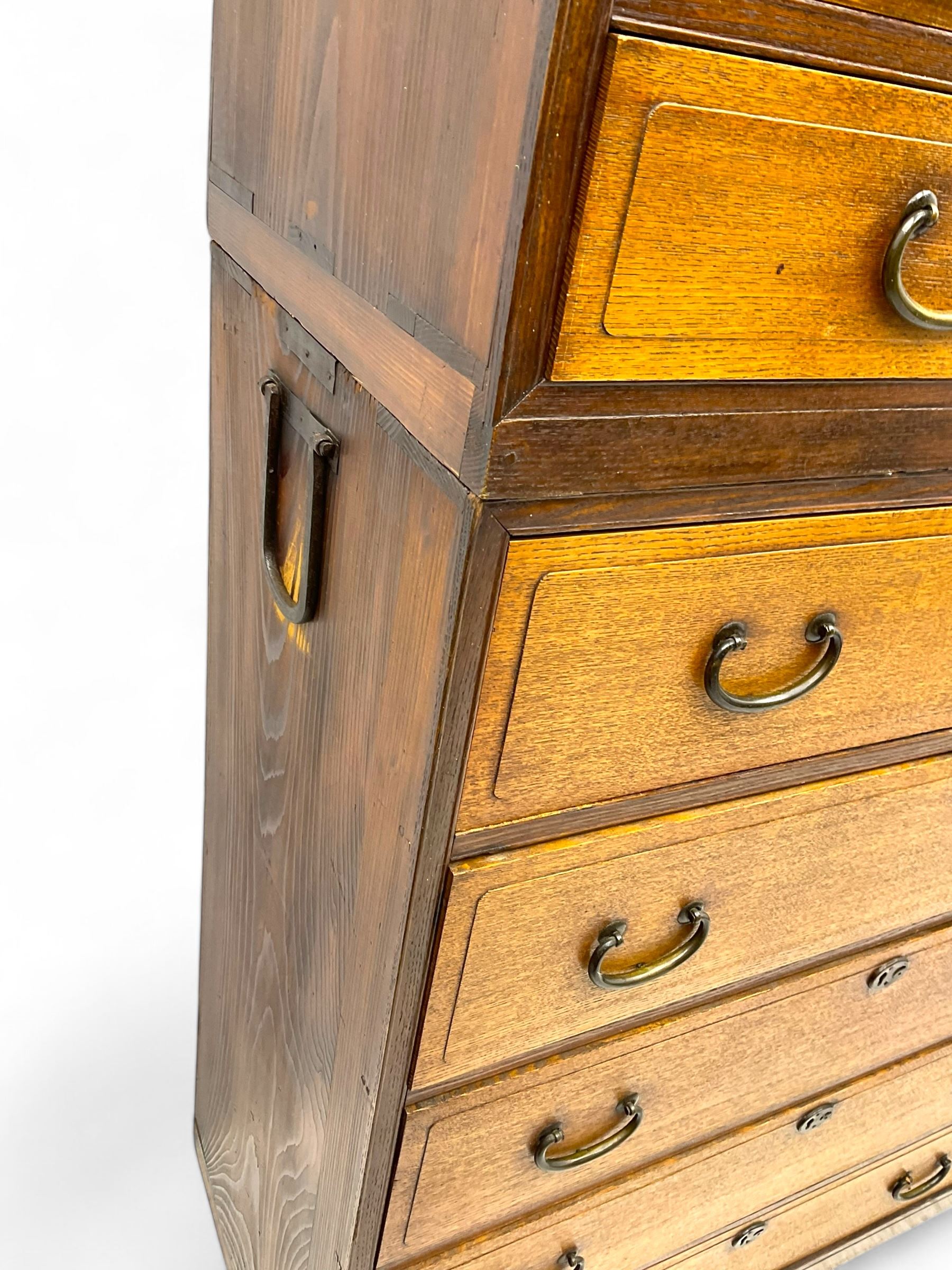 Late Meiji-period Japanese keyaki wood tansu chest, upper section with six sliding woven rattan doors over five drawers, lower section fitted with an asymmetrical arrangement of seven drawers and side cupboard with a hinged door enclosing three additional drawers, iron drop handles to sides