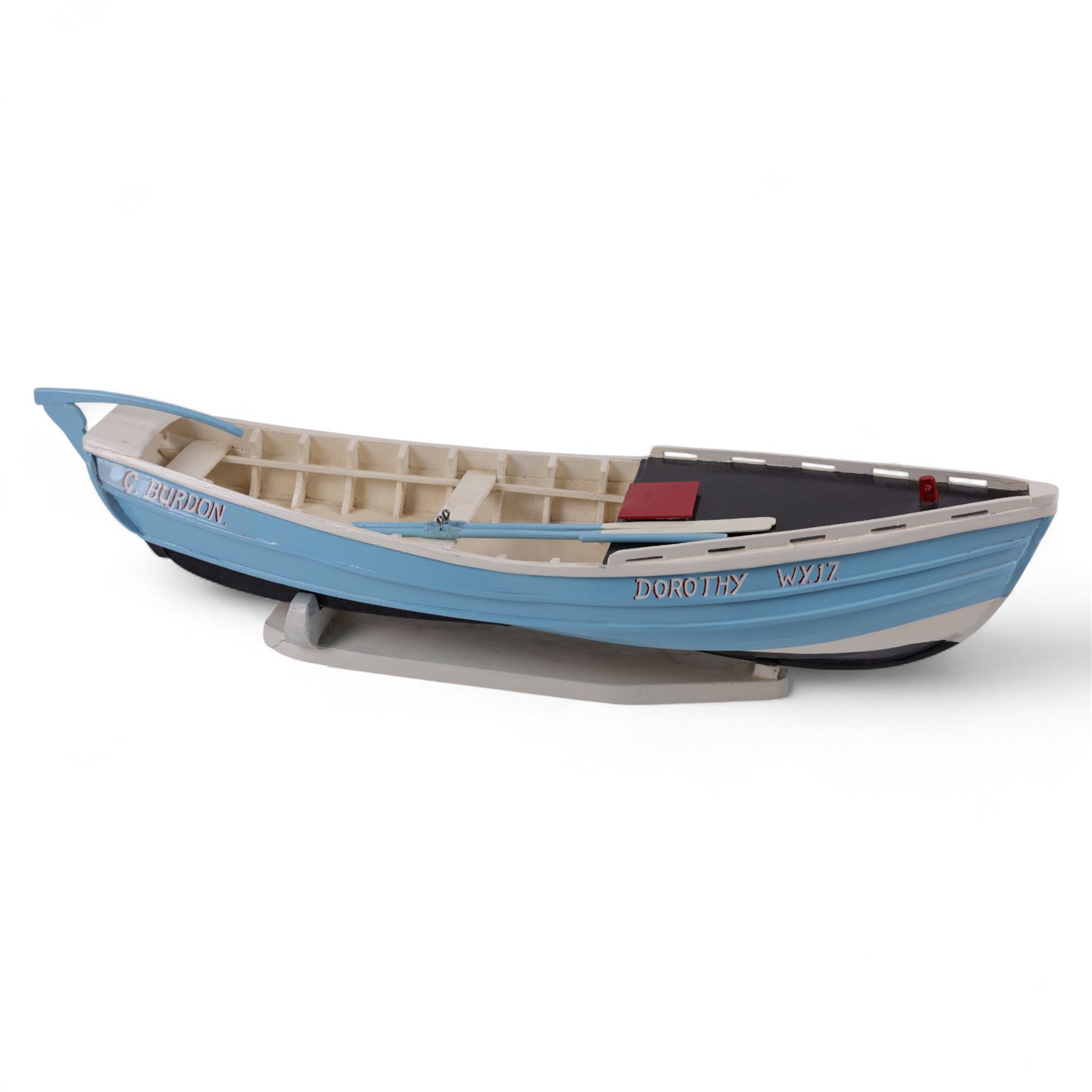 Wooden model of the Whitby fishing coble WY.17 G.Burdon 'Dorothy', painted in blue and white with red detail, with rudder and oars, on a painted wooden stand, L73cm, H20cm