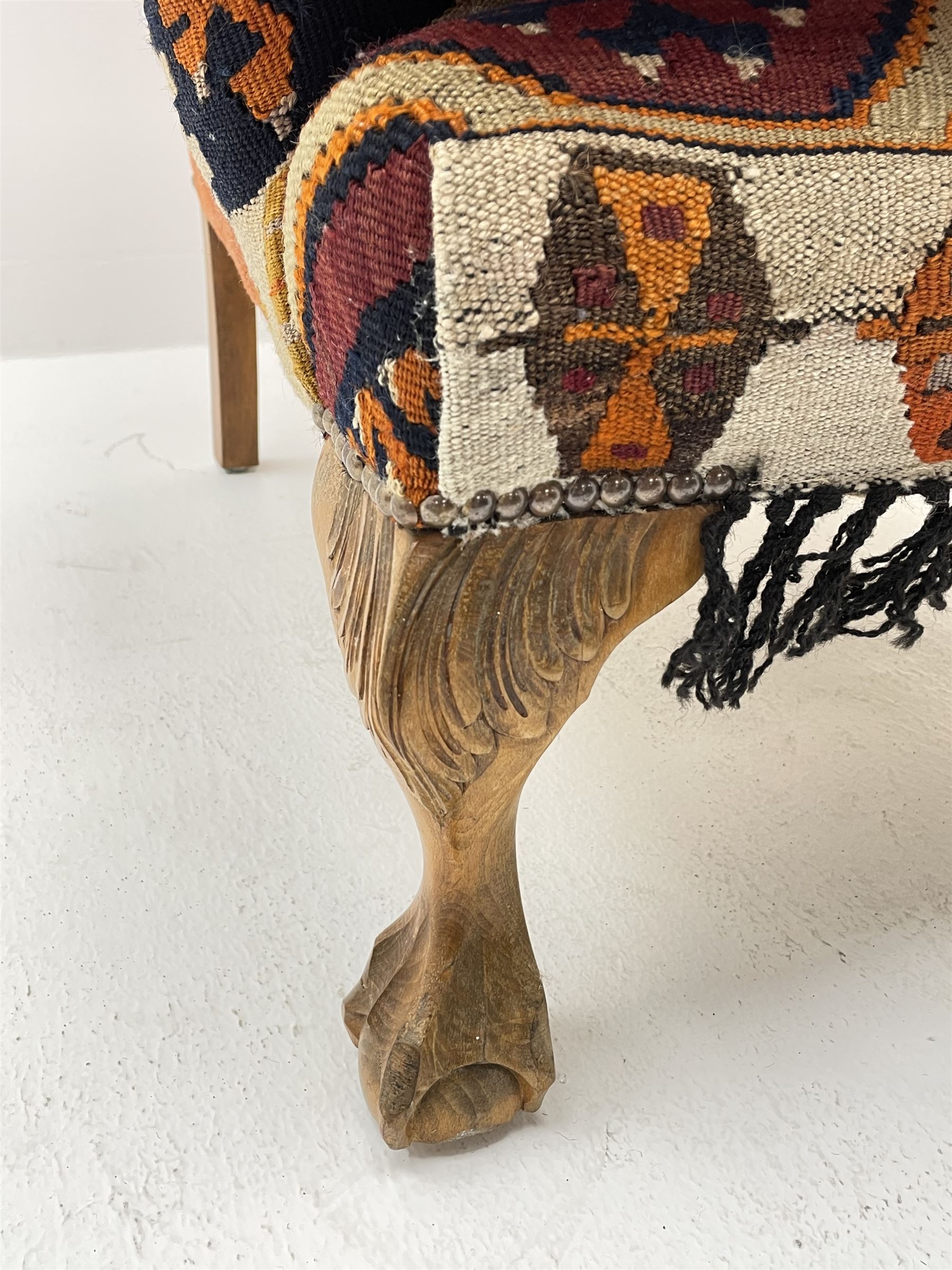 Late 20th century beech framed wingback armchair, sprung seat and back upholstered in kilim cover, acanthus carved cabriole supports with ball and claw feet