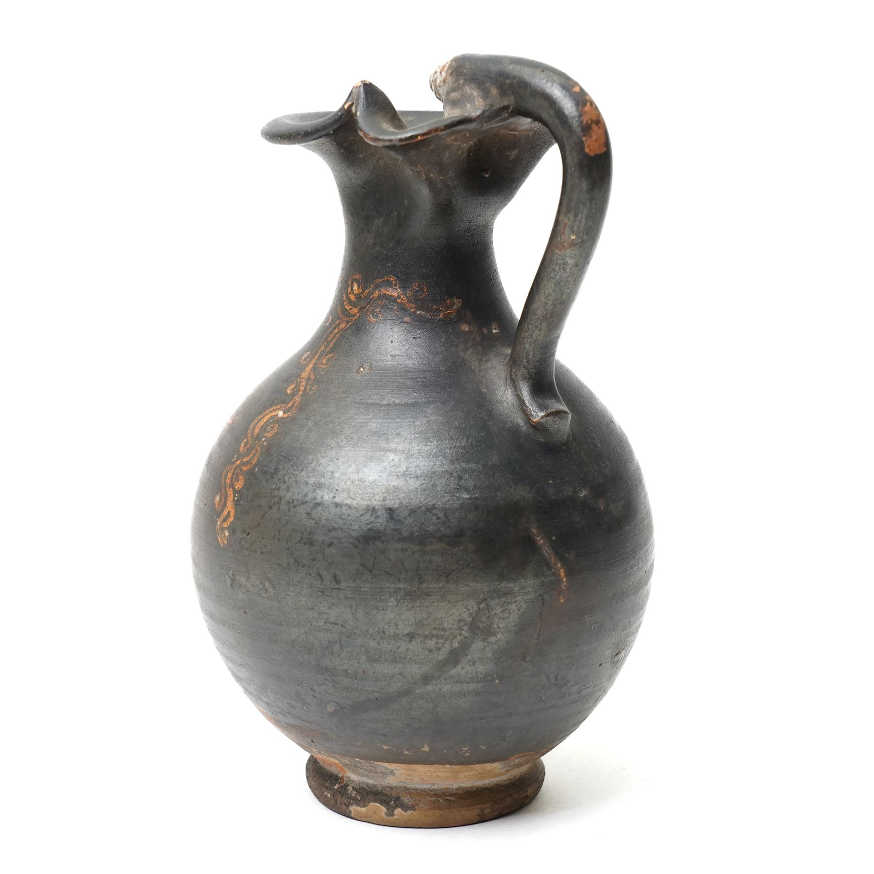 South Italian Gnathian terracotta oinochoe (jug) Apulian or Campanian (Late 4th century BC c.325-300 BC) of elegant ovoid form with trefoil mouth and single strap handle, the handle terminating in a stylised serpentine motif merging into the pouring lip, the vessel covered in a black gloss slip and decorated in added red, white and yellow with a theatrical mask, fillets and scrolling Dionysiac vine motifs, H19cm 
Notes: Gnathian ware takes its name from Egnathia in Apulia and is characterised by a black-gloss ground with added-colour decoration; the theatrical mask, fillets and vine scrolls relate to Dionysiac imagery associated with the symposium and theatre in South Italian Greek culture of the late fourth century BC. A very similar oinochoe is held in the The Metropolitan Museum of Art, object number 76.12.8