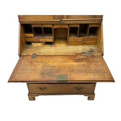 George III oak bookcase on bureau, the double arched top enclosed by two shaped glazed doors, fall-front concealing fitted interior, over four graduating cock-beaded drawers, on bracket feet