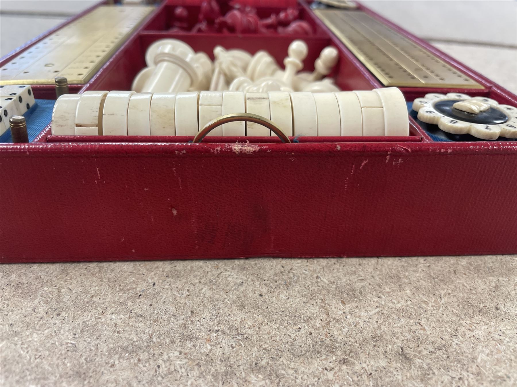 19th century walnut and brass bound games compendium box, painted to enhance the grain, of rectangular form, the hinged opening cover with rounded sides, central brass cartouche with engraved lion crest, and brass riveted straps, opening to reveal a red leather and blue silk lined compartmented interior, with fold-down games board, and lift-out tray containing playing cards, ebony turned dice towers, white and red stained bone draughts, and chess pieces, ivory dice, and ivory and ebony whist markers, and brass bezique board, cribbage board and markers, H15cm W32cm D24cm
This lot has been registered for sale under Section 10 of the APHA Ivory Act
