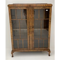 Early 20th walnut bookcase, raised shaped back, two glazed doors enclosing three shelves, cabriole feet