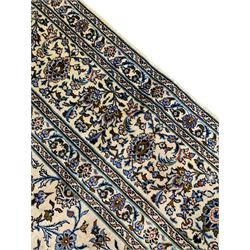 Persian Kashan ivory ground carpet, the field decorated with interlacing leafy branches and stylised plant motifs, repeating border with multiple guards