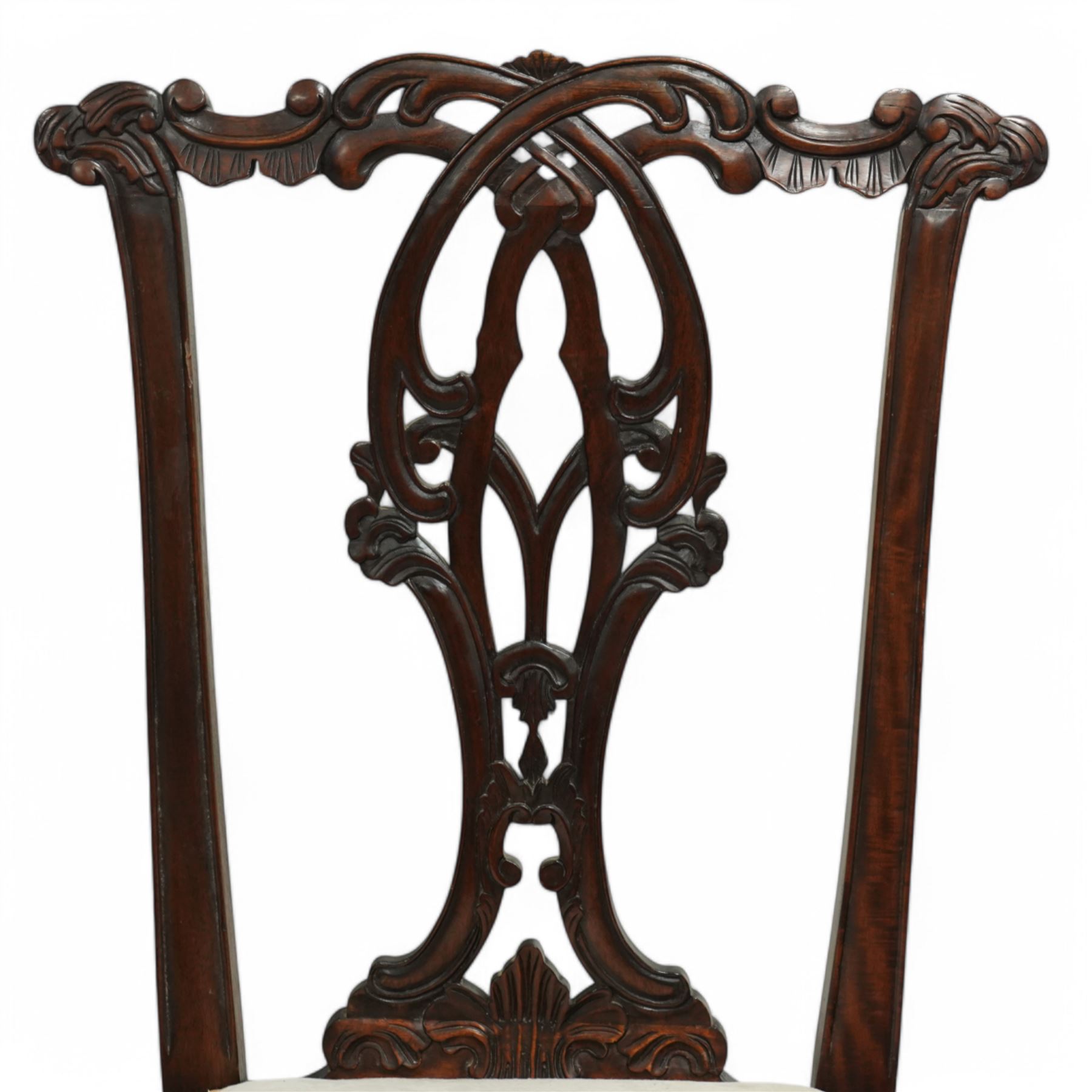 Chippendale revival mahogany dining chairs, set of six including a pair of carvers, the backs with intricately carved pierced splats beneath serpentine cresting rails, on acanthus carved cabriole front supports terminating in claw and ball feet, with cream upholstered drop-in seats