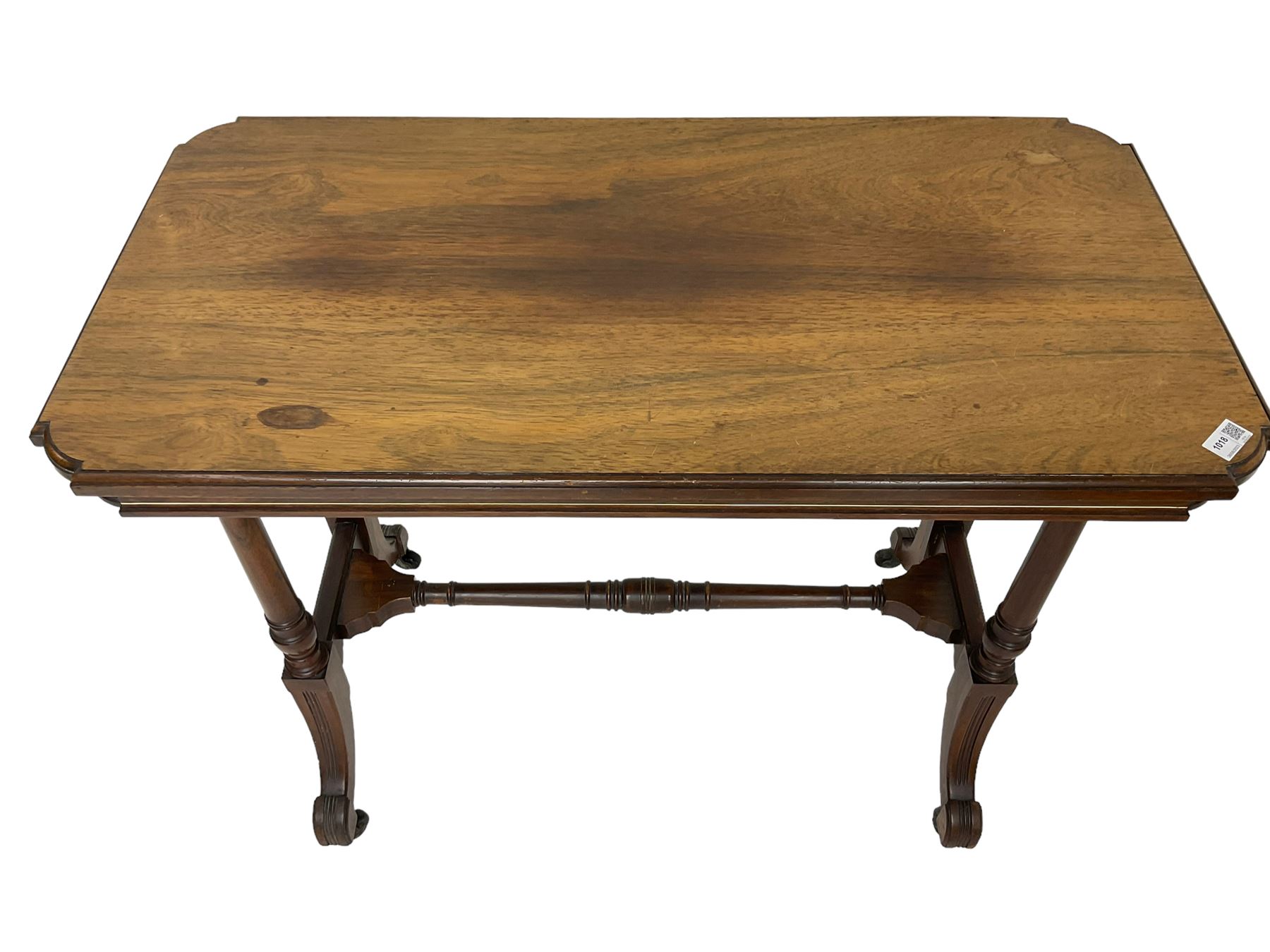Late Victorian rosewood stretcher table, the rectangular top with curved canted cornice and moulded edge, on quadruple turned pillar supports carved with foliage, joined by collar turned stretcher, on splayed moulded supports with brass and ceramic castors