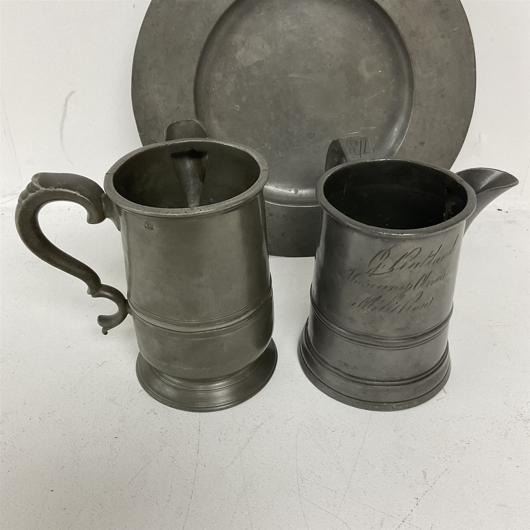 18th century pewter plate, with stamped London Superfine and crowned rose mark verso, together with two 19th century pewter side pouring tavern quart mugs, each indistinctly engraved (one 'R Harding Feathers')