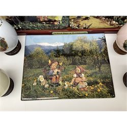 Two ceramic Hummel postcards by Goebel, both displayed on wooden easels, together nine Hummel eggs, set of four Hummel School Days plates, on wooden hanging rack, Goebel Collectors Club Member plaque etc