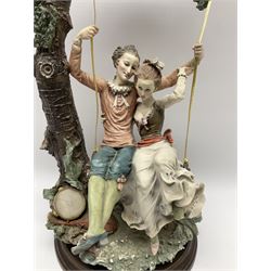 Capodimonte figural lovers on a swing, on raised circular wooden plinth, H43cm