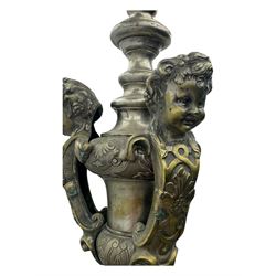 Early 20th century cast brass chandelier, the main baluster-form body surmounted by a lobed finial, with three cherubic heads and foliate scrollwork around the upper section, eight sweeping branches for lights