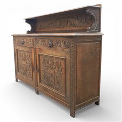 Victorian carved oak sideboard, the rectangular top with raised back carved with foliate scrolls and scroll end supports, upon a base with rectangular top with moulded edge, pair of drawers with conforming carved decoration and mask handles, and pair of carved cupboard doors, upon short stile type feet H101.5cm W183cm D54cm 