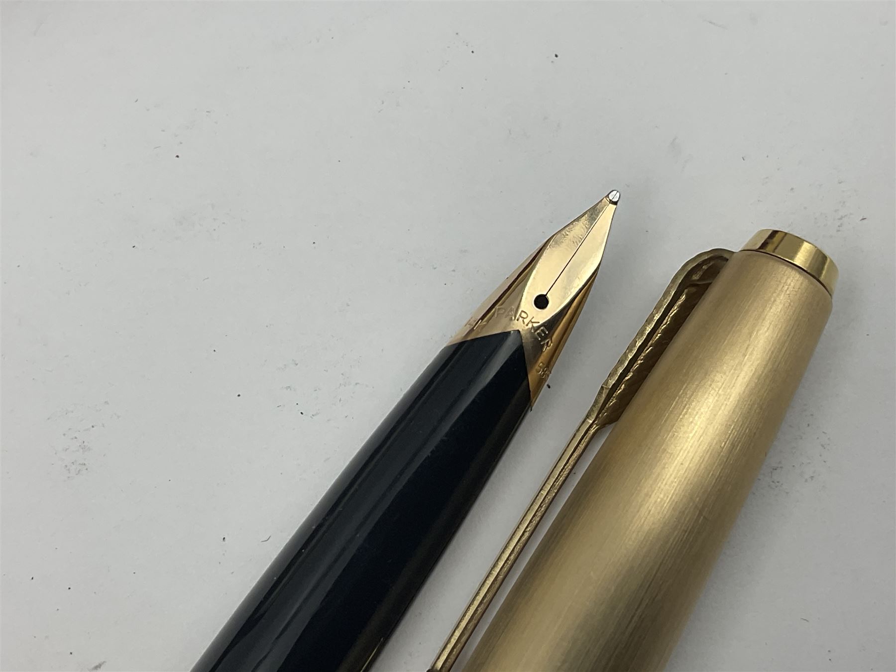 Three rolled gold Parker fountain pens, comprising an example with a gold nib marked 14K 585 and barrel with a shell stamp, a Parker 61 fountain pen with inset gold arrow to the nib, and another similar, all with striated decoration and arrow clips to the caps, L13cm, one with box