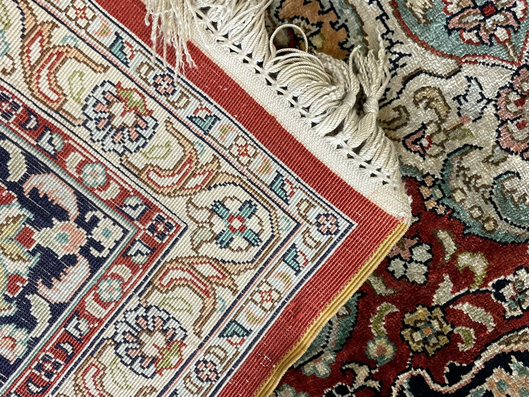 Persian silk finely knotted rug, central floral rosette medallion surrounded by curling branches decorated with palmettes, repeating pattern borders decorated with stylised plants and trailing leafy branches  