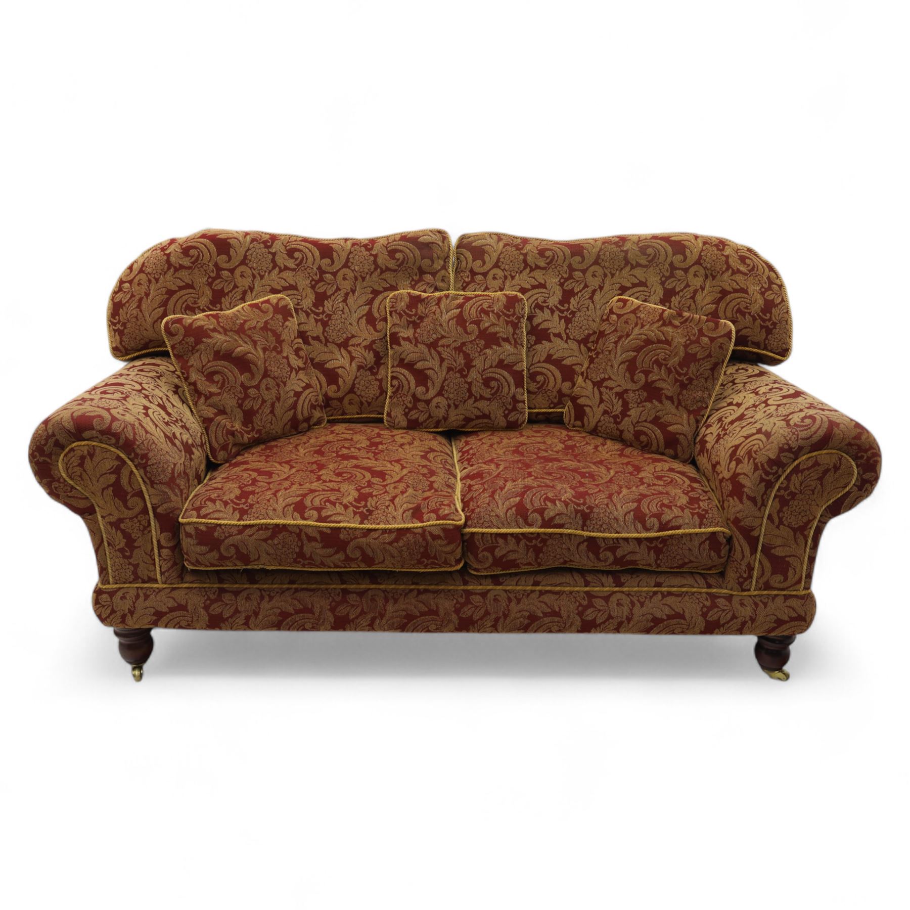 Duresta - two seat settee, upholstered in red and gold damask fabric with piped edges, scroll arms and loose feather-filled cushions, raised on turned wooden feet with brass castors