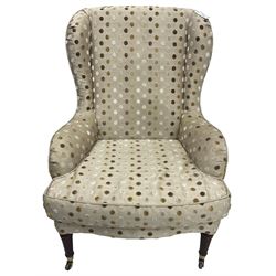 Victorian design wingback armchair, sprung seat with loose cushion upholstered in polka dot fabric, on turned supports with castors