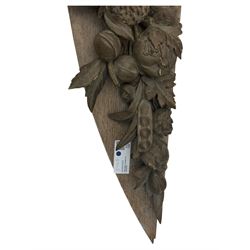 Early 20th century figural torchère, modelled as a standing putto supporting a circular top with tasselled drapery effect, raised on a circular base with foliate moulding; together with a 19th century large carved wood fragment, triangular form with high relief fruit, foliage and shell motif (H23cm, W129cm)