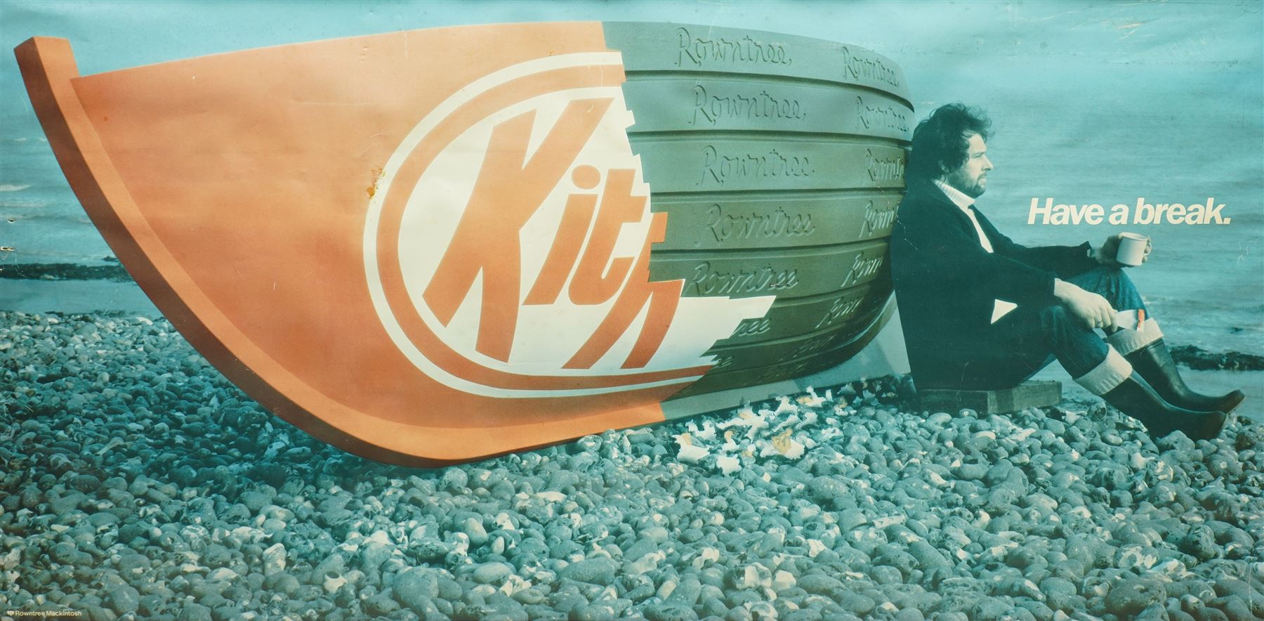 Original Rowntree Mackintosh (Rowntrees) advertising poster for KitKat - 'Have a Break', colour poster depicting a KitKat boat on a beach with a man drinking a cup of tea 38cm x 75cm 
Provenance: from the personal collection of David Lamb, former advertising manager at Rowntree Mackintosh, York