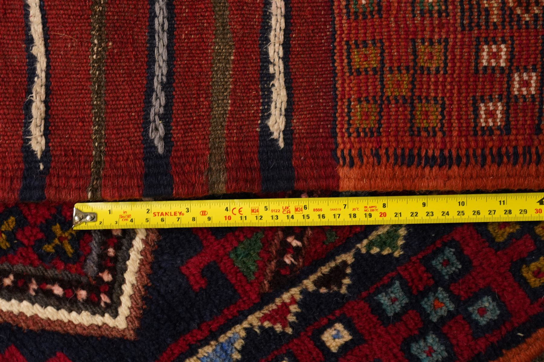 Two hand-knotted rugs, comprising Persian runner and Turkoman prayer rug, Persian hand-knotted runner, red and dark navy ground with four diamond medallions and geometric motifs, enclosed by multicoloured geometric border, striped kilim ends with fringes, H244cm, W58cm; Turkoman hand-knotted prayer rug, ivory mihrab field decorated with repeating stylised geometric motifs, enclosed by multiple geometric borders in madder red and brown, with fringed ends, H150cm, W93cm