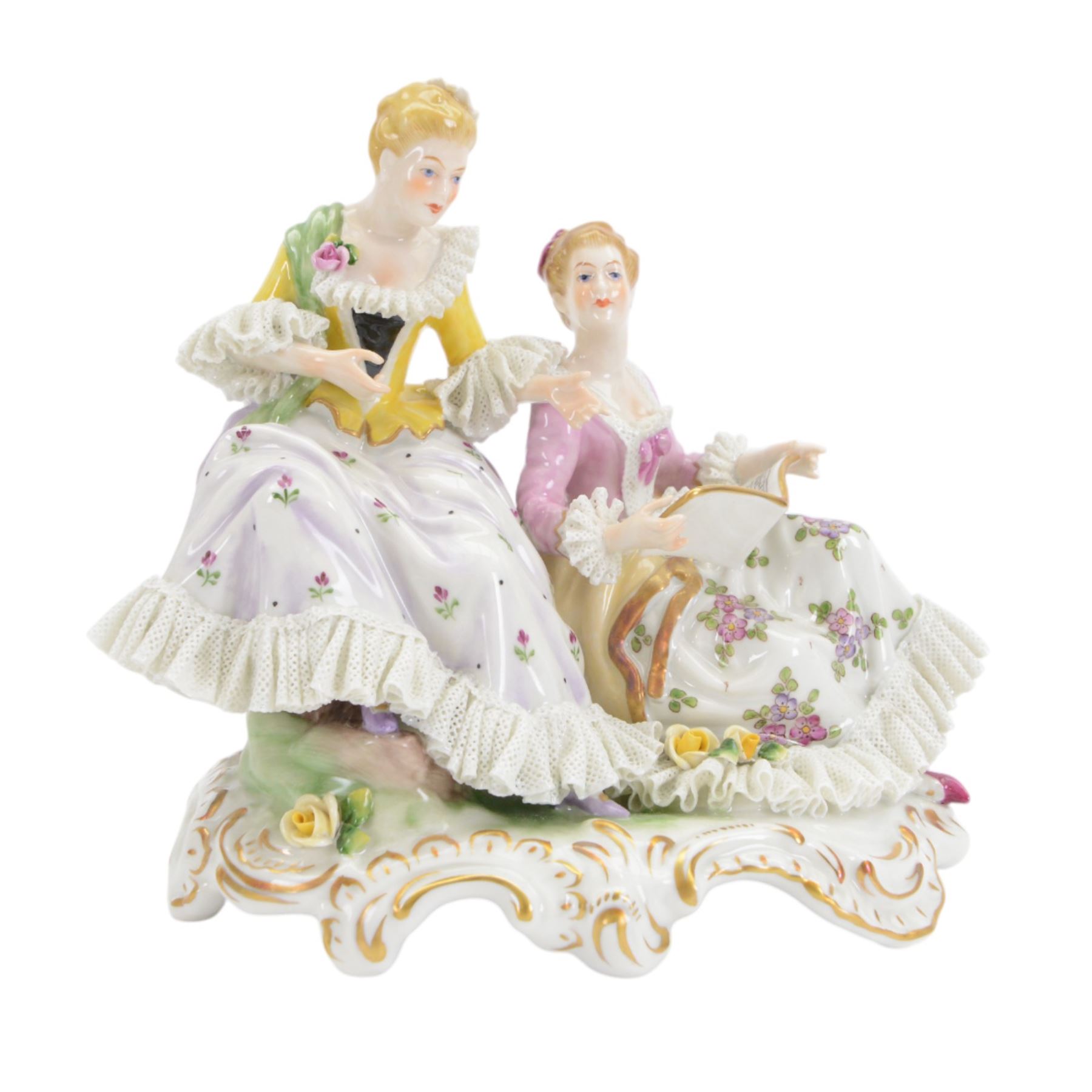 Three Continental lace figures, comprising a figure group modelled as two seated female figures reading, with lace trimmed gowns, H19.5cm, the other two examples modelled female figure with arms outstretched, the lace gowns encrusted with flowers, taller example H21cm