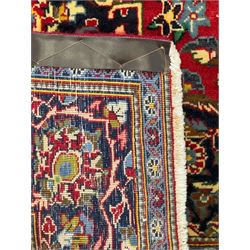 Central Persian Kashan crimson ground rug, central indigo pole medallion surrounded by sparsely placed bouquets interconnected with foliate branches, the guarded border with repeating palmette and Boteh motifs with interwoven scrolling patterns, framed by guard stripes