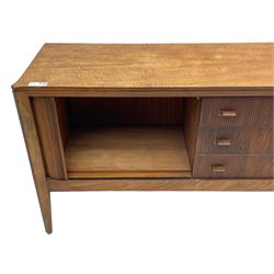 Mid-20th century teak sideboard, three central drawers flanked by tambour roll doors, the righthand side fitted with slides, on tapering feet